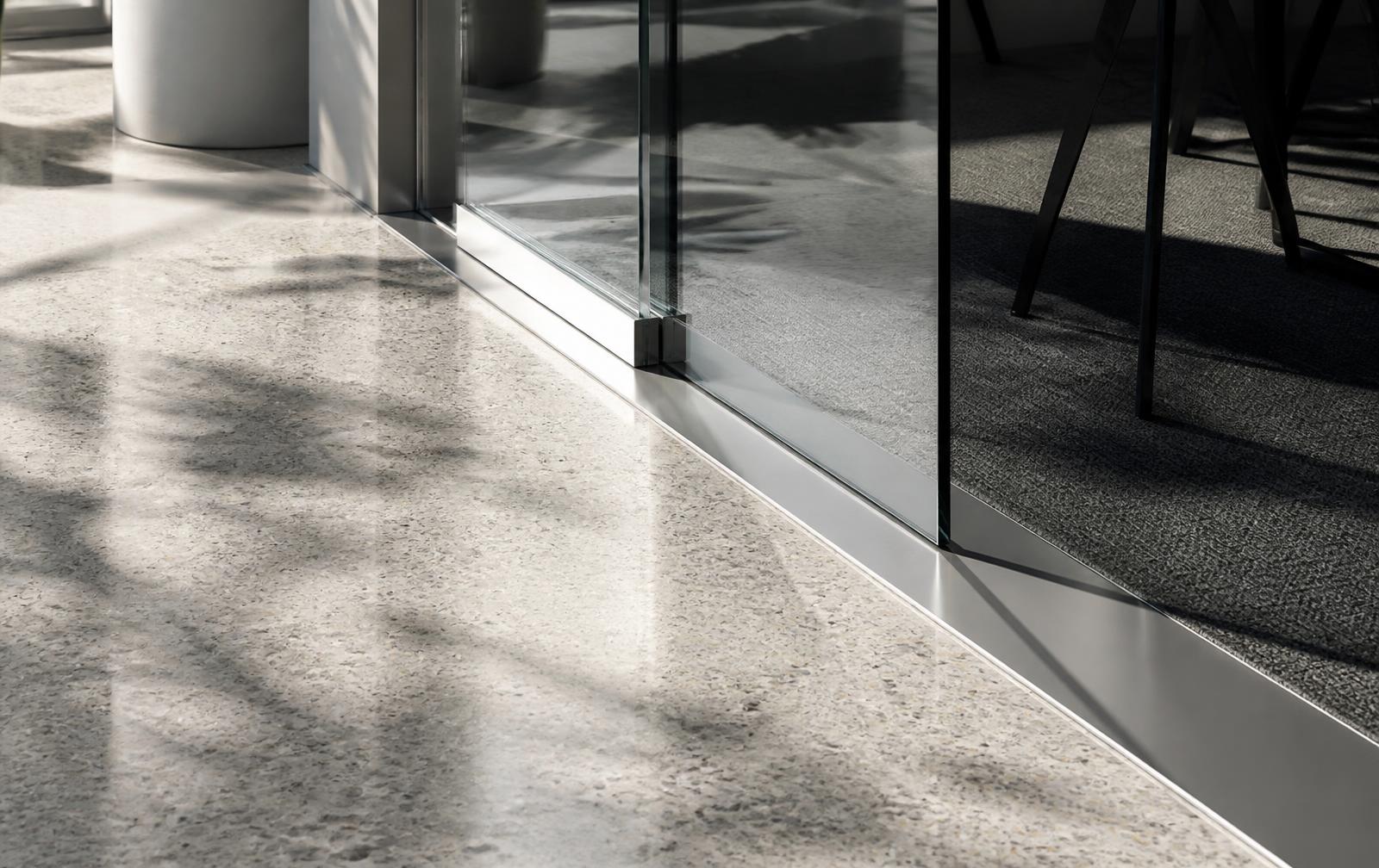 Terrazzo floor meeting a glass wall in morning light